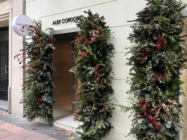 Fachada de la pastelería Álex Cordobés, con el cartel y plantas en la entrada